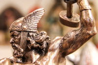 Une statue de Thor portant un casque et soulevant un poids.