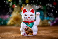 Une statue du chat Maneki Neko, la paume de la patte gauche levée.