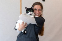 Une ostéopathe tenant un chat dans ses bras et souriant