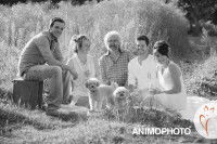 Photo en noir et blanc d'une famille et ses deux Caniches dans un champ