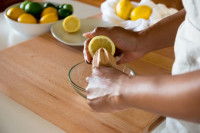 Une femme presse un citron sur une table en bois
