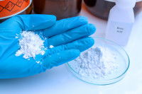 Une main avec un gant tient de l'acide borique en poudre