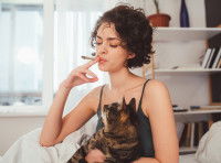 Une femme fume une cigarette en tenant son chat dans les bras