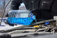 Un homme verse de l'antigel dans le radiateur d'une voiture