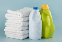 Deux bouteilles d'eau de javel à côté d'une pile de serviettes