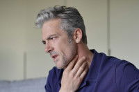 Un homme avec des cheveux gris souffre d'une angine
