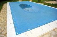 Une piscine dans un jardin protégée par une bâche