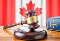 Un maillet et un livre de droit posés devant un drapeau du Canada