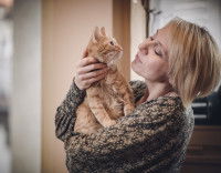 Une femme tient un chat roux dans ses bras