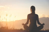 Silhouette d'une femme qui pratique du yoga en montagne