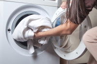 Une femme met ses draps dans la machine à laver