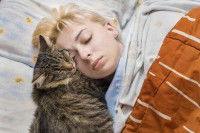 Une femme blonde dort avec son chat