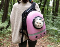 Une femme portant un chat dans un sac à dos équipé d'un hublot