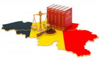 Un maillet, des livres juridiques et une balance sur une carte de la Belgique aux couleurs du drapeau