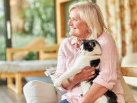 Une femme sénior garde un chat noir et blanc à son domicile