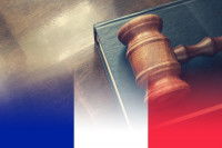 Un livre de droit et un maillet derrière un drapeau français