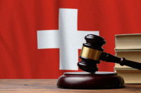 Un maillet sur un bureau devant le drapeau suisse