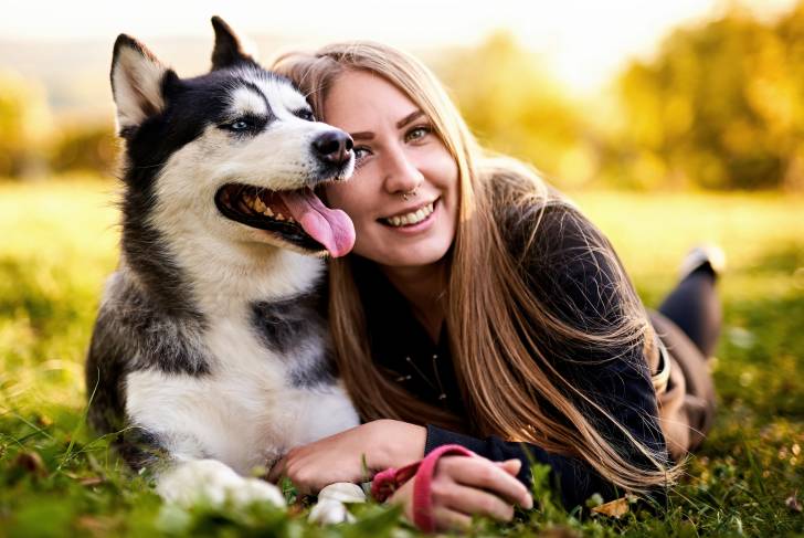 Un Husky Sibérien allongé à côté de sa propriétaire