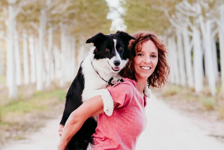 Un Border Collie sur le dos de sa propriétaire 